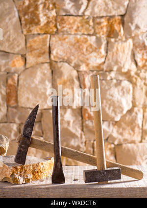 Hammer mason tools of stonecutter masonry work in a contruction stone wall Stock Photo