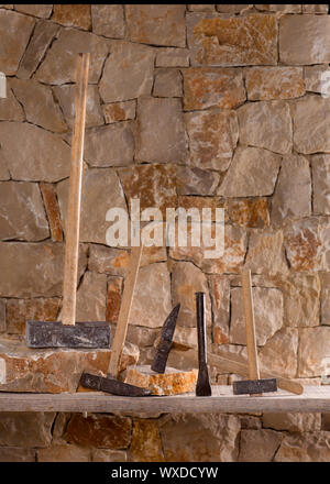 Hammer mason tools of stonecutter masonry work in a contruction stone wall Stock Photo