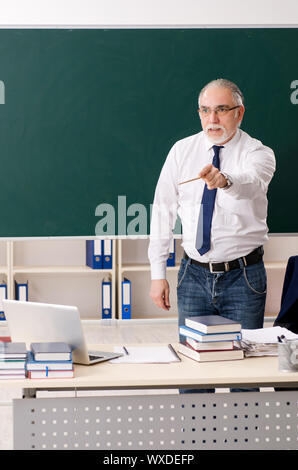 Senior teacher with books and chalkboard. Old smiling professor on ...