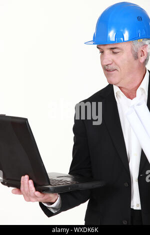 Engineer holding his laptop and rolled-up drawings Stock Photo