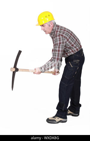A mature construction worker using a pickaxe. Stock Photo