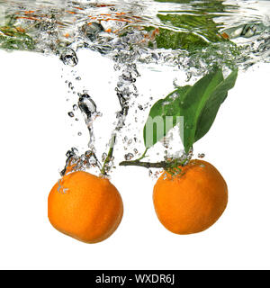 tangerines dropped into water with bubbles on white Stock Photo