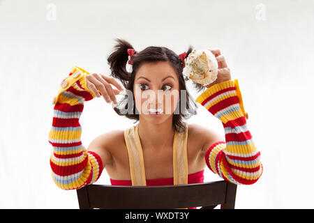 Beautiful Latina girl eating a cupcake with her fingers looking cross eyed, isolated Stock Photo