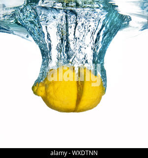 Fresh lemon dropped into water with bubbles isolated on white Stock Photo