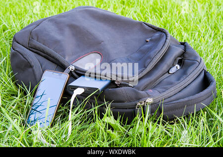 power bank charges a smartphone on the grass Stock Photo