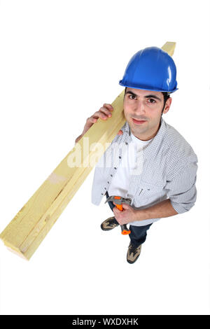 high angle shot of carpenter carrying planks on his shoulder with hammer Stock Photo
