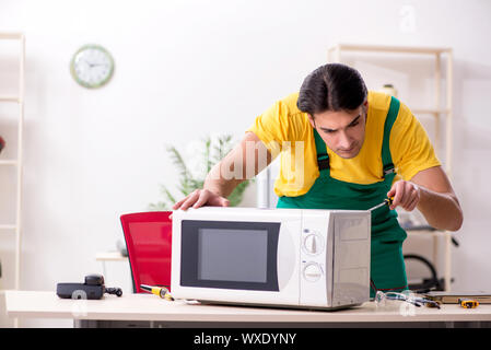 Young repairman repairing microwave in service centre Stock Photo