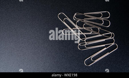 Metal paper clips, office supply on black background Stock Photo