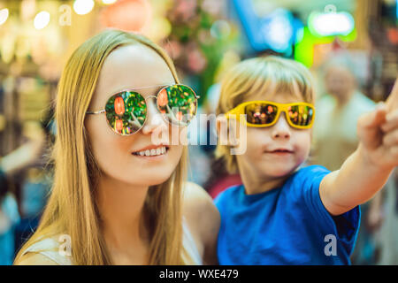 Mom and son celebrate Chinese New Year look at Chinese red lanterns. Chinese lanterns are reflected in glasses Stock Photo