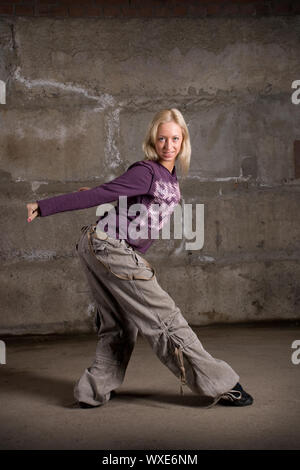 Beautiful hip hop girl dancing over grey brick wall Stock Photo