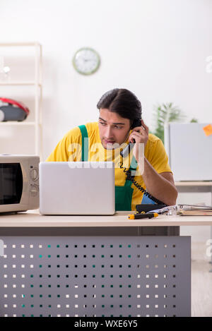 Young repairman repairing microwave in service centre Stock Photo