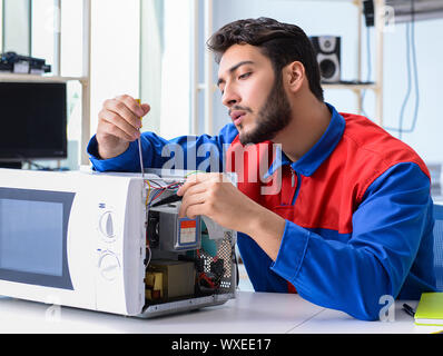 Young repairman fixing and repairing microwave oven Stock Photo