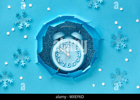 Happy New Year 2020! Aarm clock in paper hole, flat lay on blue color paper Stock Photo