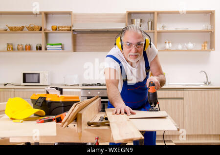 Aged contractor repairman working in the kitchen Stock Photo