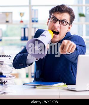 Angry aggressive businessman with bullhorn loudspeaker in office Stock Photo
