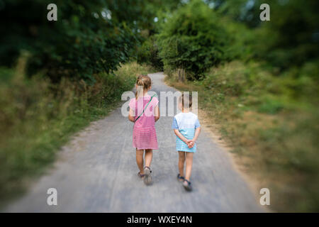 Brother and sister walking together on a forest path Stock Photo