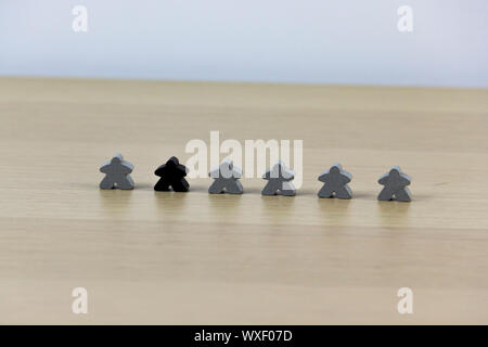 Gray gaming pieces and a black meeple, diversity concept Stock Photo