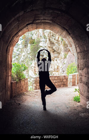 Woman practicing yoga in a dark tunnel Stock Photo