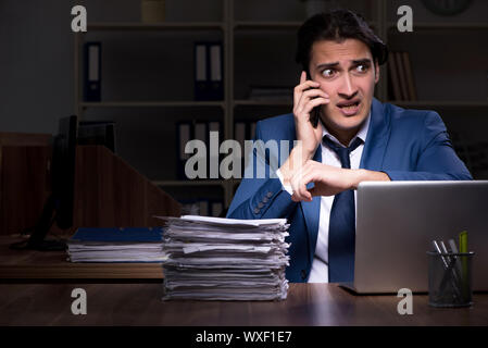Young male employee working night in the office Stock Photo