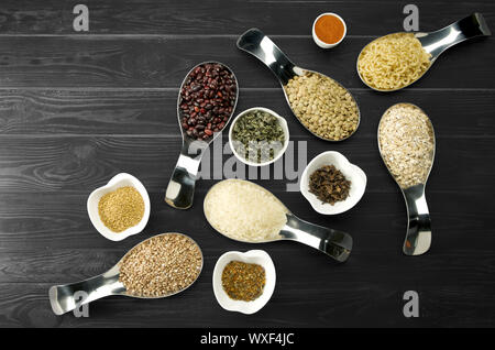 BEANS RICE BUCKWHEAT SEEDS LENTILS SPICES IN SPOONS ON DARK WOODEN BACKGROUND Stock Photo
