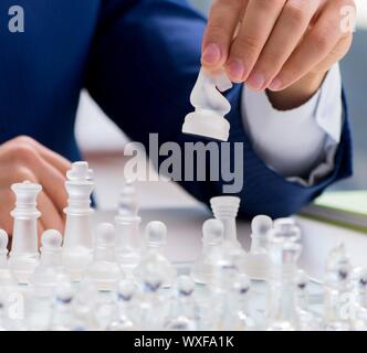 Young businessman playing glass chess in office Stock Photo