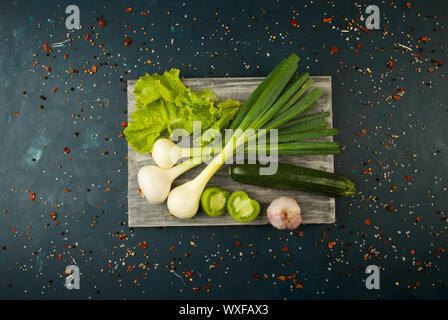 FRESH VEGETABLES AND SPICES ON A WOODEN BOARD ON A DARK STONE BACKGROUND. THE CONCEPT OF VINTAGE. SPICES THE YOUNG CORN ASPARAGU Stock Photo