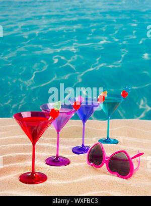 colorful cocktail in a row with cherry on tropical sand beach of turquoise sea Stock Photo