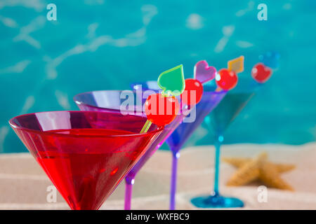 colorful cocktail in a row with cherry on tropical sand beach of turquoise sea Stock Photo