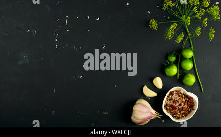 TOMATO SPICES GARLIC AND DILL ON A DARK BACKGROUND. BRANCH OF GREEN TOMATOES SPICED WITH GARLIC AND DILL ON A DARK SURFACE. Stock Photo