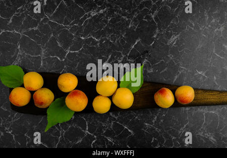 RIPE APRICOTS LYING ON A DARK BOARD ON A DARK BACKGROUND Stock Photo