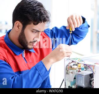 Young repairman fixing and repairing microwave oven Stock Photo