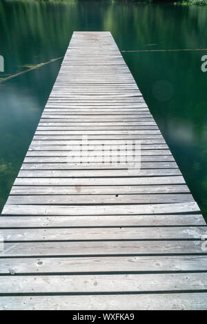 long wooden pier leads out into a mountain lake in Arosa Stock Photo