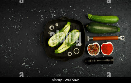 Fresh green zucchini in a pan on a dark table. The view from the top. Copy space.
