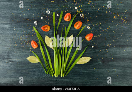 BOW ON THE BACKGROUND. GREEN BOW OF THE ONIONS, WHITE ONIONS AND TOMATO ON A STRONG WOODEN SURFACE. CONCEPT VEGETABLE PICTURE. V Stock Photo