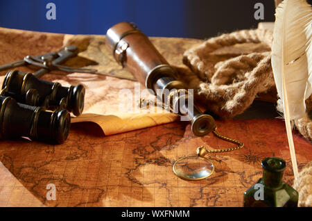 A telescope with a compass and various objects lying on an old paper map Stock Photo