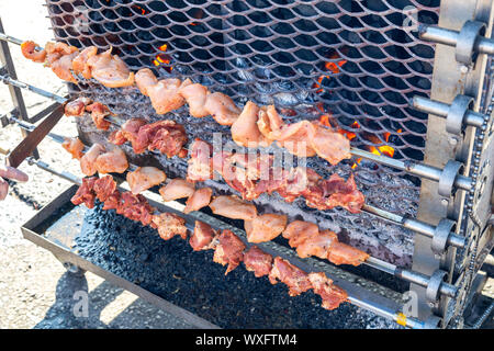 Grilled appetizing kebab cooking on metal skewers. Shashlik made of slices of meat during of cooking on the mangal over hot charcoals outdoors, street Stock Photo