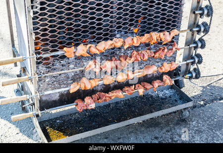 Grilled appetizing kebab cooking on metal skewers. Shashlik made of slices of meat during of cooking on the mangal over hot charcoals outdoors, street Stock Photo