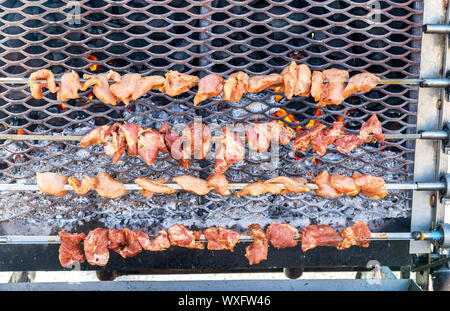 Grilled appetizing kebab cooking on metal skewers. Shashlik made of slices of meat during of cooking on the mangal over hot charcoals outdoors, street Stock Photo