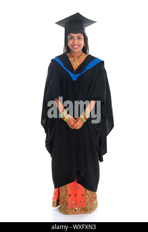 dress for graduation day in india Full body happy Indian university student in graduation gown and cap standing isolated on white background Stock Photo