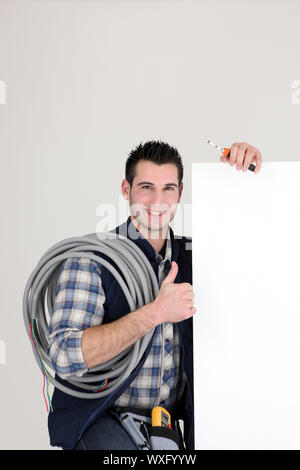 Thumbs up from an electrician with a blank board Stock Photo
