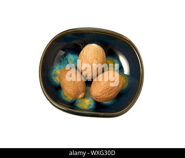 Nutmeg in a bowl isolated on a white background. Seasoning on isolate. View from above. Close up view of nutmeg. Stock Photo