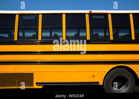 American typical school bus side view on blue sky day Stock Photo