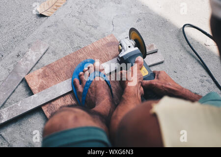 Working man cutting metal bar with circular saw. High angle view. Stock Photo