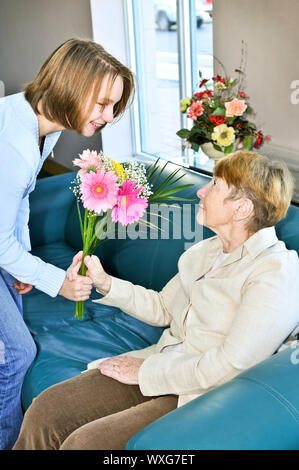 Granddaughter bringing colorful flowers to her grandmother Stock Photo