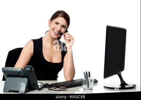Young pretty female support staff attending clients queries Stock Photo