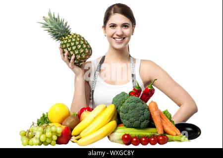 Fit pretty smiling female holding pineapple in one hand and posing Stock Photo