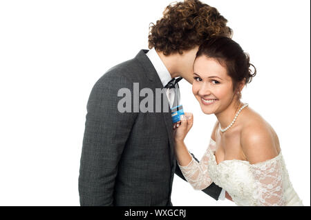 Young groom whispering into the ears of a gorgeous bride holding cash card Stock Photo