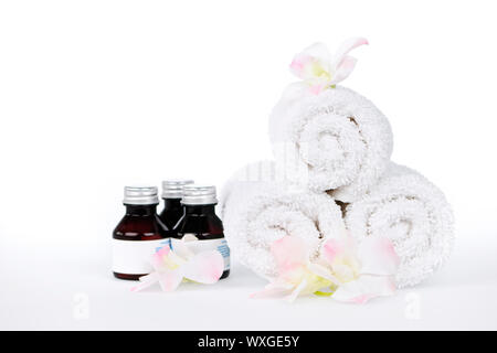 White rolled up spa towels and body care products with orchid flowers Stock Photo