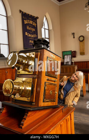 UK, County Durham, Beamish, Museum, Pit Village, Francis Street, visitor in Wesleyan Methodist chapel admiring large Victorian mahohany and brass doub Stock Photo