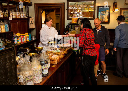 UK, County Durham, Beamish, Museum, Town, Jubilee Confectioner’s shop visitors inside at counter buying sweets Stock Photo